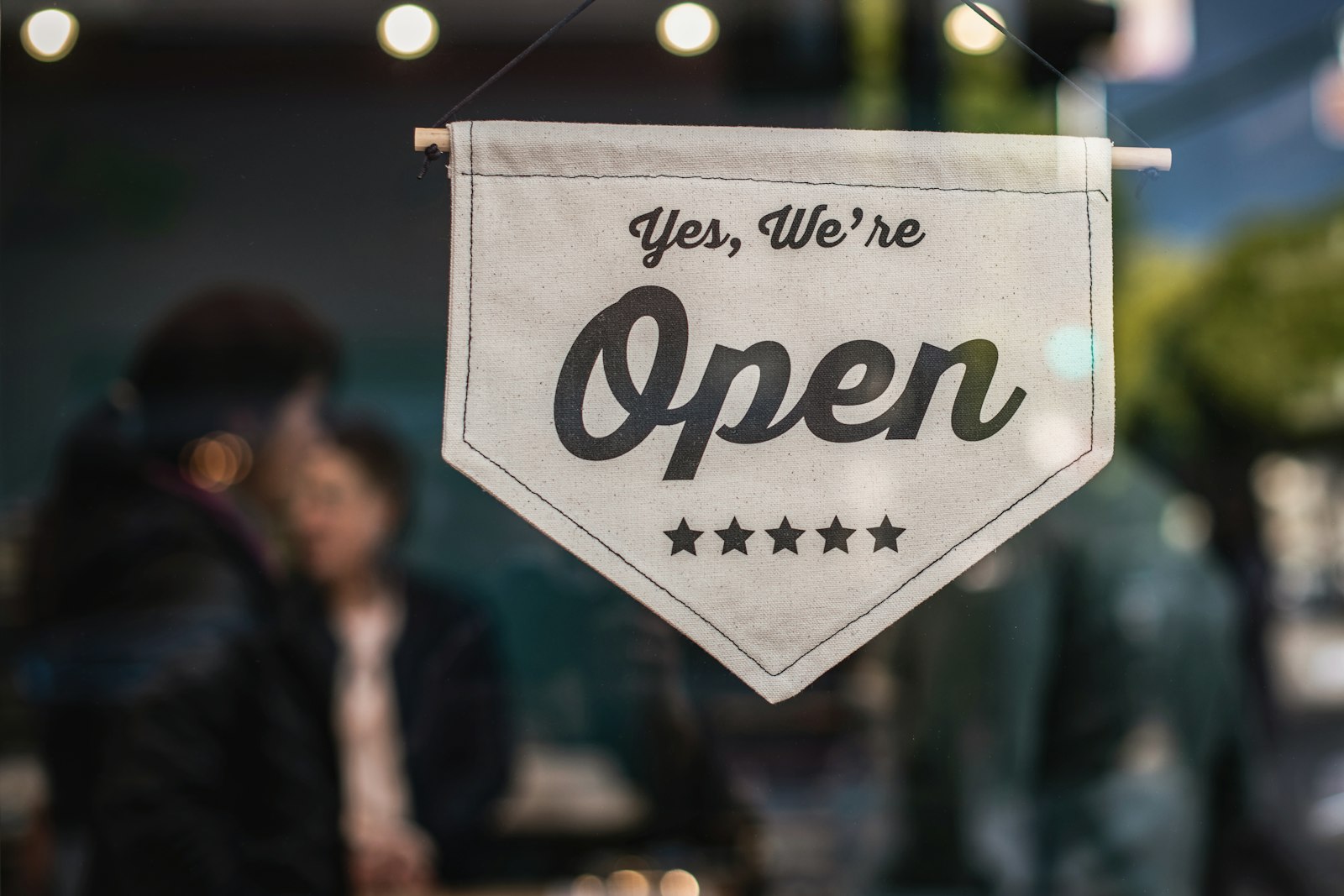 Open sign hanging in a small business shop window